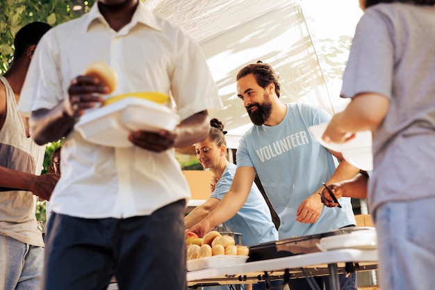 Freundliche Freiwillige bei der Lebensmittelaktion sind damit beschäftigt, Lebensmittelspenden für die Verteilung zu sortieren und zu verpacken und verkörpern den Geist des Gebens zur Bekämpfung des Hungers. Benachteiligte Obdachlose erhalten humanitäre Hilfe.