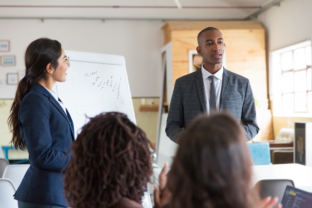 Freundliche junge Lautsprecher, die nahes whiteboard stehen