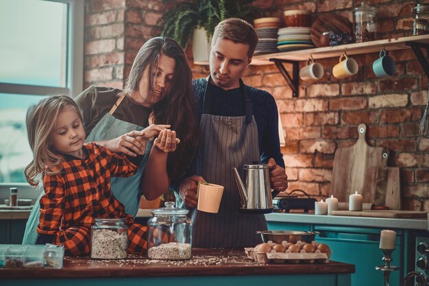 Freundliche, positive Familie, die den Morgen in der Küche verbringt, sie kochen Frühstück.