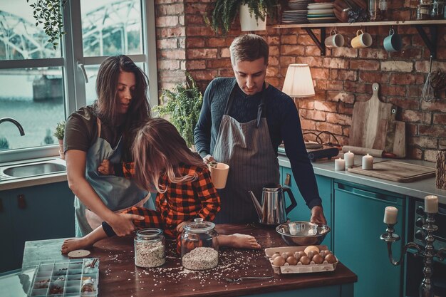 Freundliche, positive Familie, die den Morgen in der Küche verbringt, sie kochen Frühstück.