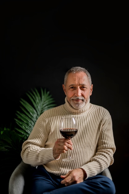 Freundlicher älterer Mann mit einem Glas Wein