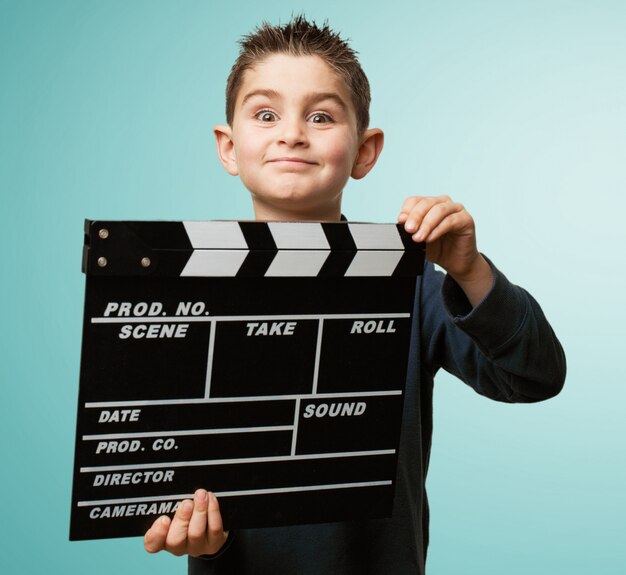 Freundlicher kleiner Junge mit einem clapperboard spielen