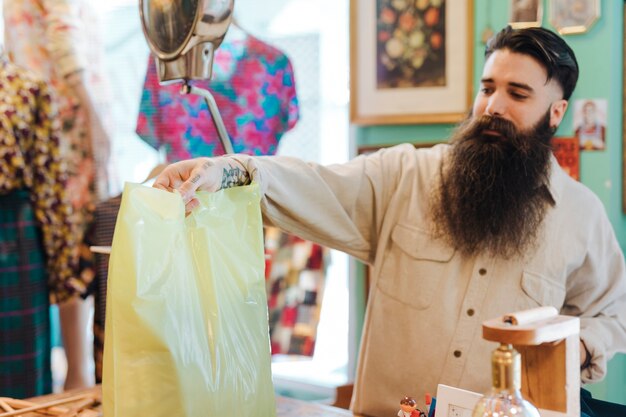 Freundlicher Ladenangestellter übergibt einem Kunden seine Tasche im Bekleidungsgeschäft