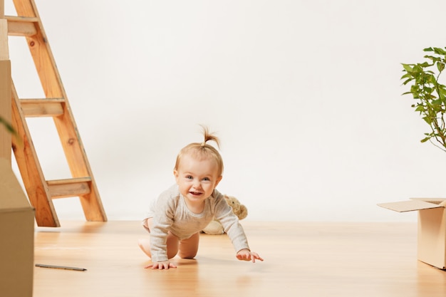 Freundliches blauäugiges Baby, das drinnen auf dem Boden sitzt