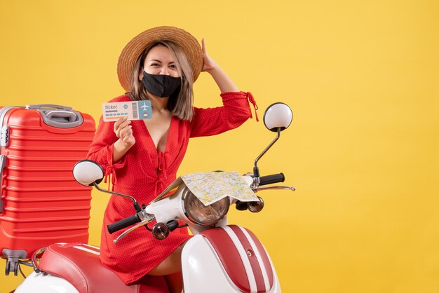 freute sich junge Dame mit schwarzer Maske auf Moped mit rotem Koffer mit Ticket