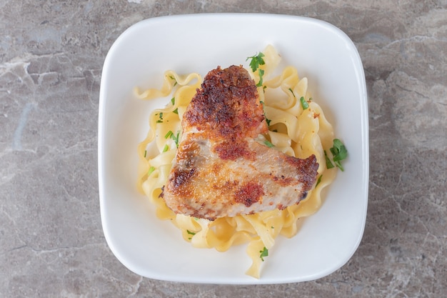 Fried Chicken Wingover Spaghetti auf dem Teller, auf dem Marmor.