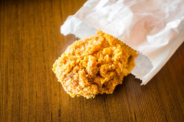 Fried Chicken Wings in Papiertüte auf Holztisch.