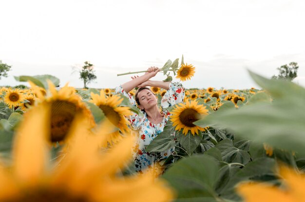 Friedliche Frau, die im Sonnenblumenfeld aufwirft
