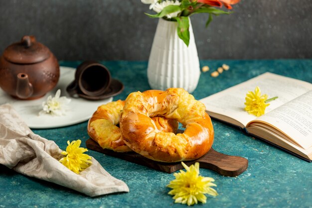 Frisch gebackene Brötchen in runder Form, gelbe Blumen und offenes Buch