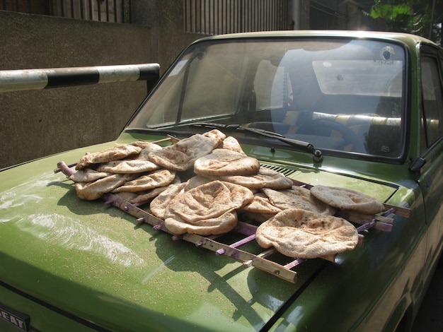 Frisch gebackene Laibe mit ägyptischem Fladenbrot zum Verkauf auf der Vorderseite eines grünen Autos auf einer Straße