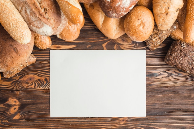 Frisch gebackenes Brot mit leerem Weißbuch auf hölzernem Schreibtisch