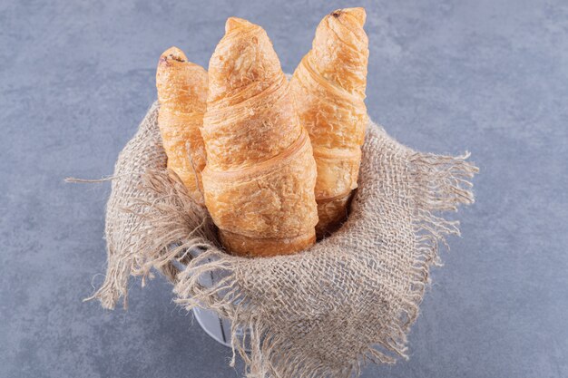 Frisch gebackenes Croissant auf Sack innerhalb des grauen Eimers