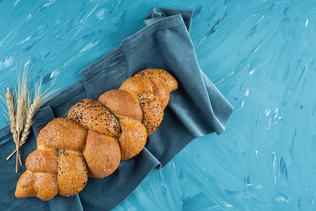 Frisch gebackenes geflochtenes Brot auf einer dunklen Tischdecke.