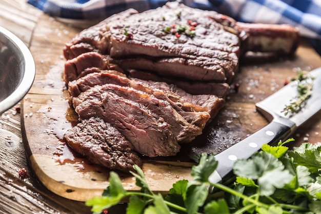 Frisch gegrilltes tomahawk-steak auf schieferplatte mit salzpfeffer-rosmarin und petersilienkräutern. geschnittene stücke saftiges rindersteak.