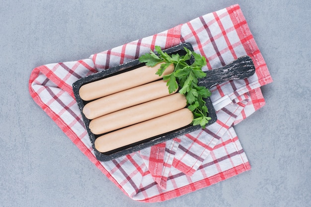 Frisch gekochte Wurst auf schwarzem Holzschneidebrett.