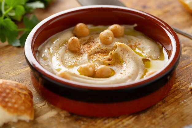 Frisch gemachter orientalischer klassischer Hummus, serviert in einer Schüssel auf dem Tisch.