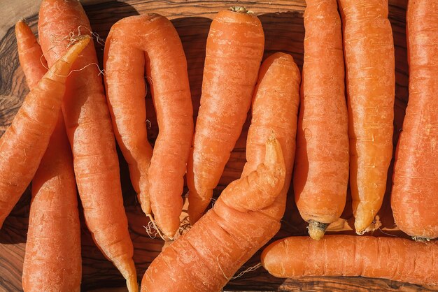 Frisch gepflückte Bio-Karotten auf einem Holzschneidebrett Draufsicht vegane Salatzubereitung