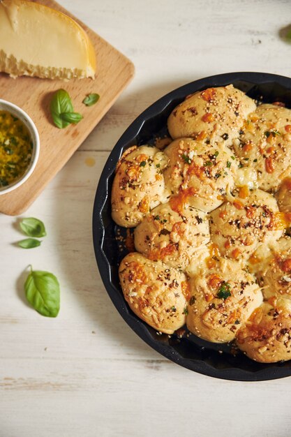 Frisch zubereitetes leckeres Käse-Blase-Pizza-Brot mit Zutaten und Käse auf einem weißen Tisch