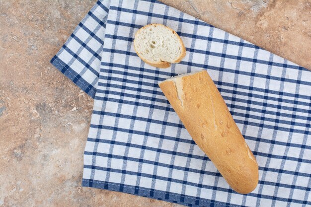 Frische Baguettescheibe auf gestreifter Tischdecke