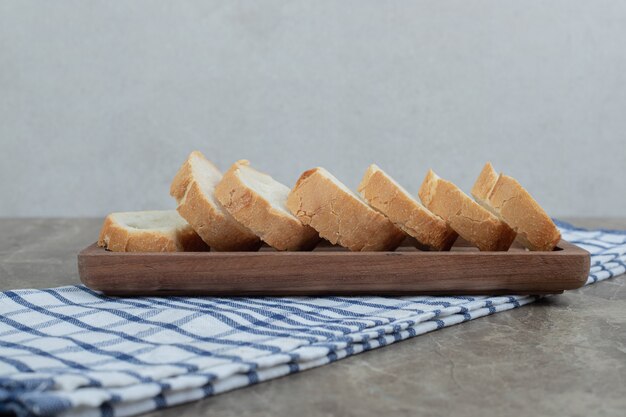 Frische Baguettescheiben auf Holzteller mit Tischdecke. Hochwertiges Foto