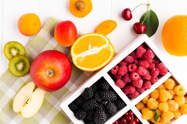 Kostenloses Foto frische beeren flach auf tischdecke mit früchten legen