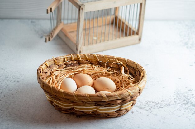 Frische Bio-Eier auf Korb auf grauer Oberfläche.