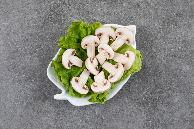 Frische Bio-Pilze mit Salat auf weißem Teller
