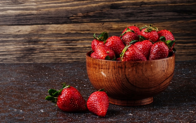 Frische Erdbeere der Seitenansicht in der Schüssel auf hölzernem Hintergrund