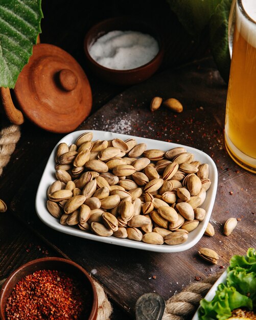 Frische Erdnüsse der Draufsicht mit grünem Salat auf dem hölzernen Schreibtisch-Snack-Nussfoto