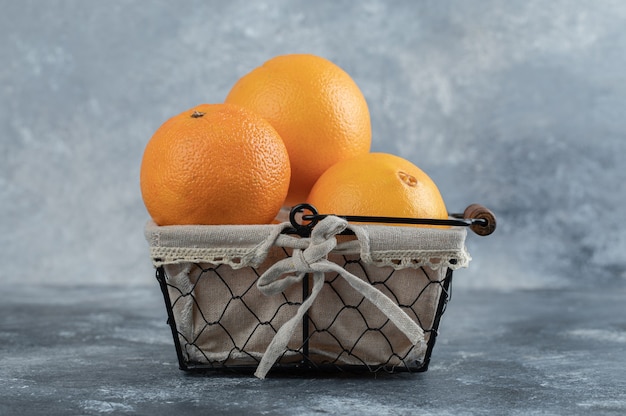 Frische erfrischende Orangen im Korb auf Marmortisch.