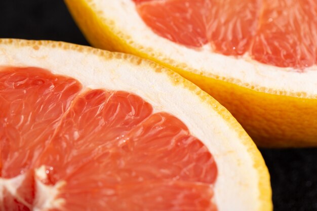 Frische Früchte saftig ausgereifte reife Stücke der leckeren Grapefruit isoliert auf dunkel