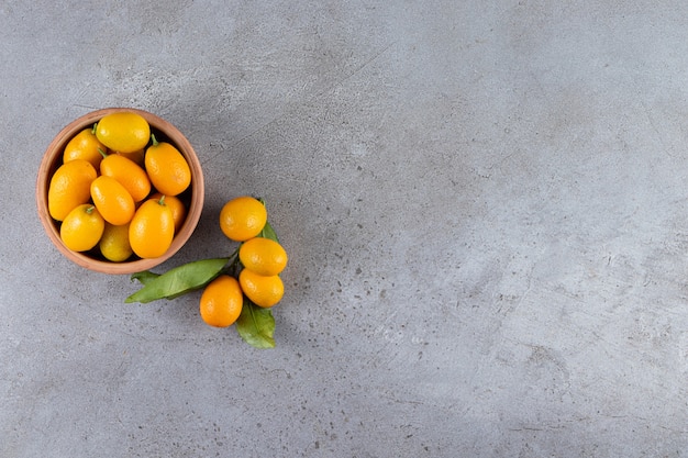 Frische ganze citrus cumquat früchte mit blättern in holzschale gelegt