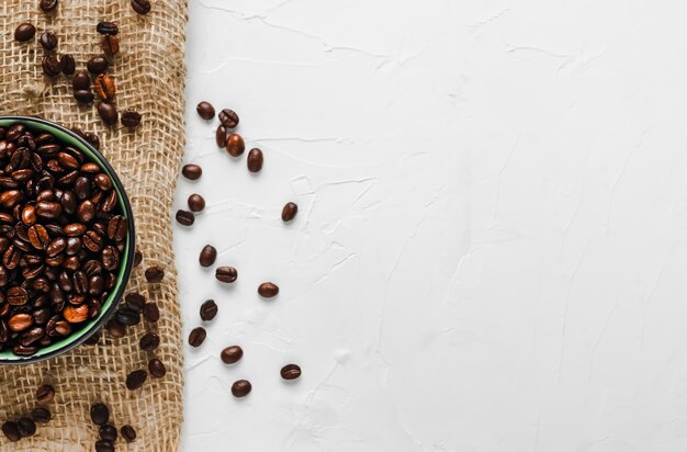 Frische, geröstete Kaffeebohnen in einer Tasse auf Sackleinen