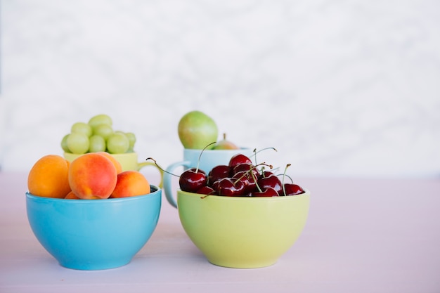 Frische gesunde Früchte in der Schüssel auf weißer Oberfläche