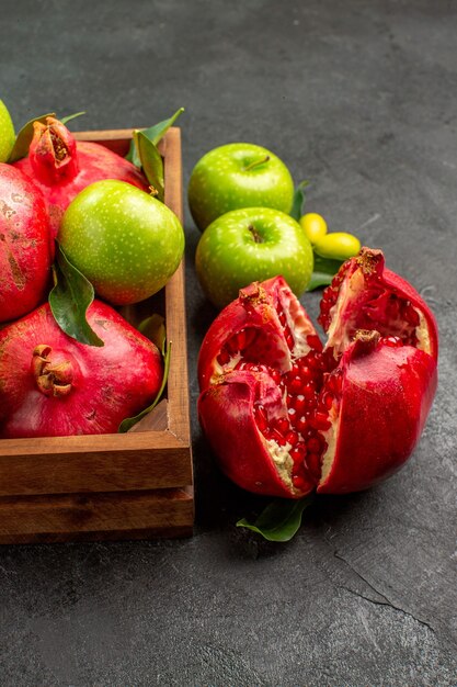 Frische Granatäpfel der Vorderansicht mit grünen Äpfeln auf reifer Fruchtfarbe der dunklen Oberfläche