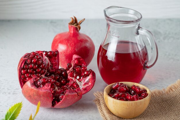 Frische Granatäpfel mit Saft. Ganze oder geschnittene Granatäpfel auf grauer Wand.