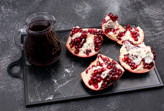 frische Granatapfelsaft Karaffe auf dunklem Tablett