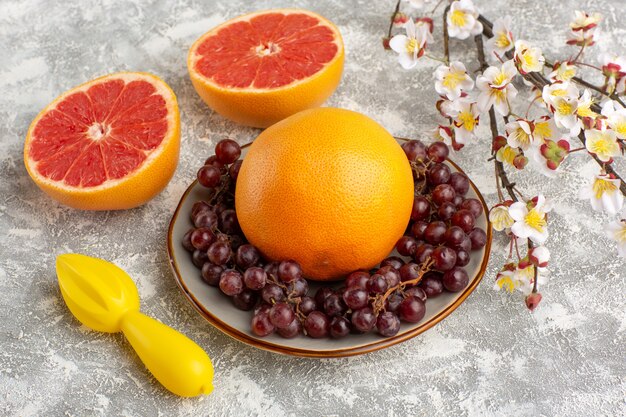 Frische Grapefruitringe der Vorderansicht mit Trauben auf weißer Oberfläche