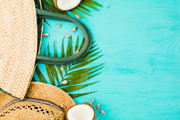 Kostenloses Foto frische grüne pflanze verlässt nahe handtasche und hut mit kokosnuss