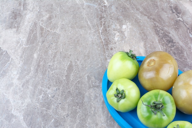 Kostenloses Foto frische grüne tomaten und eingelegte tomaten auf blauem teller.