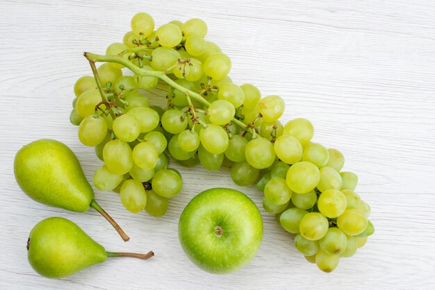 Frische grüne Trauben der Draufsicht mit Birnen und Apfel auf dem weißen Schreibtischfruchtgrünfarbensommer