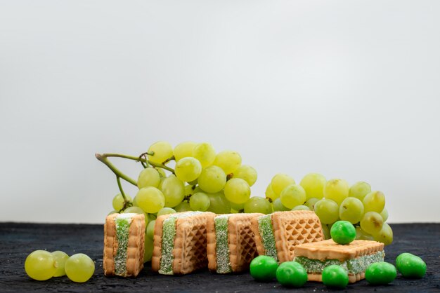 Frische grüne Trauben der Vorderansicht sauer saftig und weich mit Keksen auf der dunklen Hintergrundfrucht reifen Pflanze