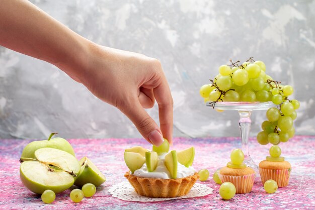 frische grüne Trauben ganze saure und köstliche Früchte mit kleinen Kuchen, die von Frauen auf Licht genommen werden