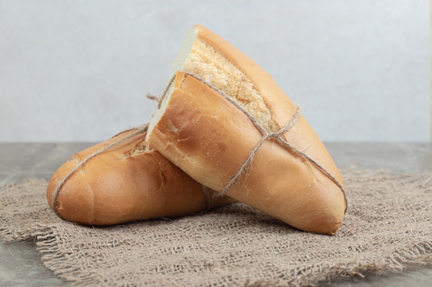 Frische halbe Brotstücke mit Seil auf Sackleinen gebunden. Hochwertiges Foto