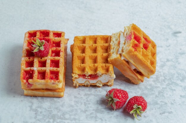 Frische hausgemachte Waffelscheiben mit Himbeere auf grauer Oberfläche.