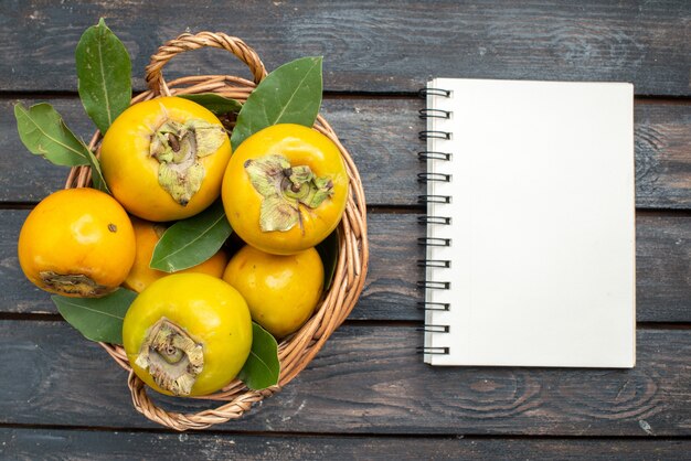 Frische Kakis der Draufsicht innerhalb des Korbs auf dem Holztisch, Frucht weich reif