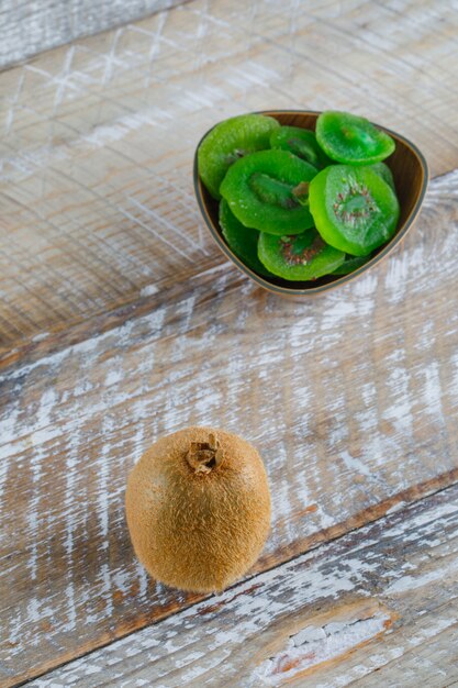 Frische kiwi mit getrockneten scheiben auf holztisch, hohe winkelansicht.