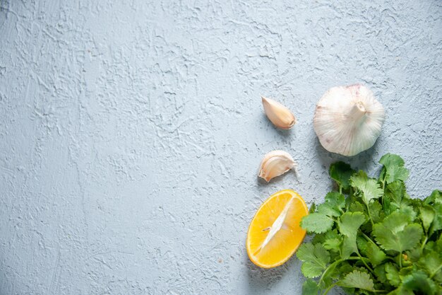 Frische Knoblauchzehen der Draufsicht mit Grün und Zitrone auf hellem Hintergrundnahrungsmittelpflanzenpfeffersauergewürzgemüse