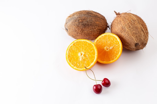 Frische Kokosnüsse der Vorderansicht zusammen mit geschnittenem Orange auf Weiß