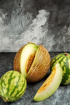 Frische melone der vorderansicht mit wassermelone auf dem dunklen hellen hintergrund